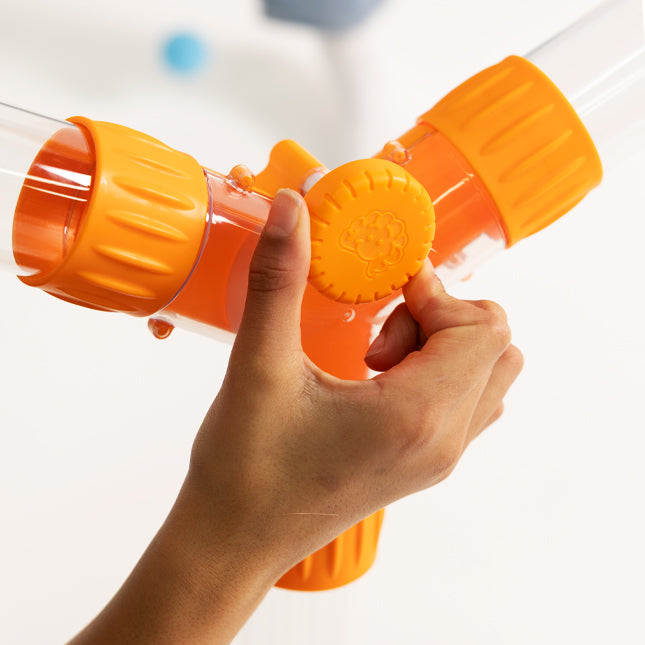 Hand holding an orange and clear toy water gun against a white background