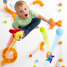 Child playing with colorful toy tubes on a white floor