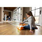Child playing with a toy on a wooden floor in a home setting