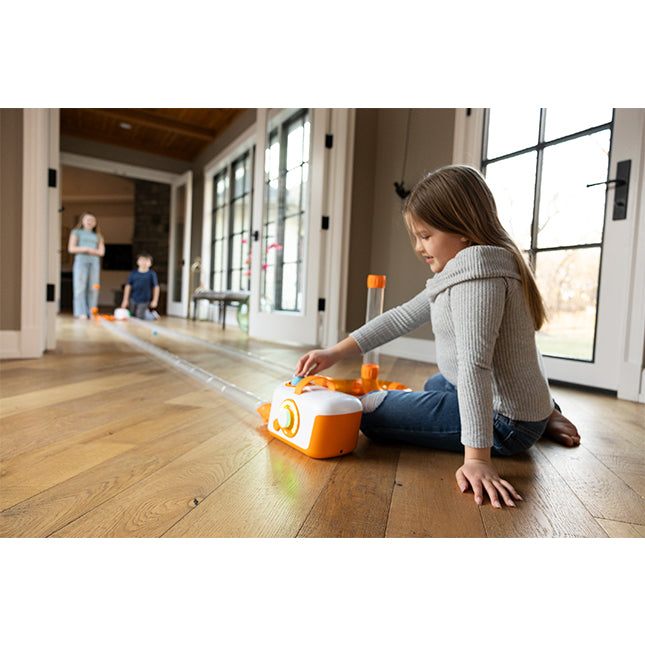 Child playing with a toy on a wooden floor in a home setting