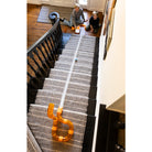 Stair runner with orange clips on a staircase, children playing at the top.