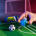 Hand holding a toy soccer player on a miniature soccer field.