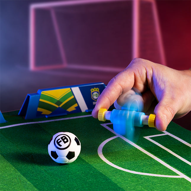 Hand holding a toy soccer player on a miniature soccer field.