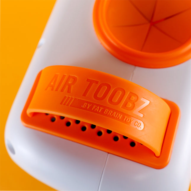 Close-up of an orange and white Air Toobz belly fat burner device, showing the embossed brand name and vented orange plastic trim against a bright yellow background.