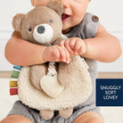 Baby holding a teddy bear toy on a white fluffy surface
