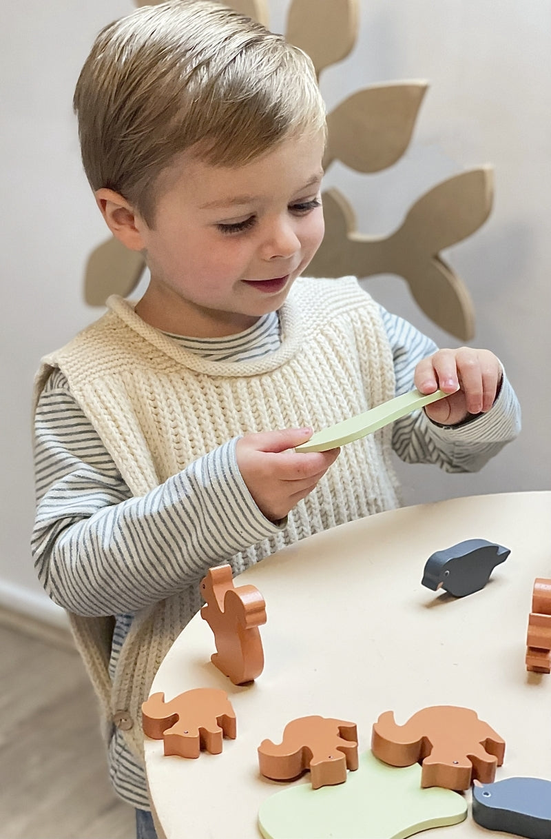 Child playing with wooden animal shapes on a table