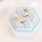 Gold ice skate earrings on a light blue hexagonal cushion