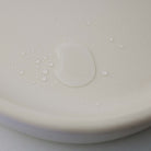 Close-up of a white plastic component with water droplets on a light gray background