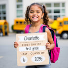 Young girl holding a sign for her first day of first grade with school buses in the background.