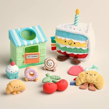 Set of colorful plush toys including a bakery, cake, and various food items on a beige background