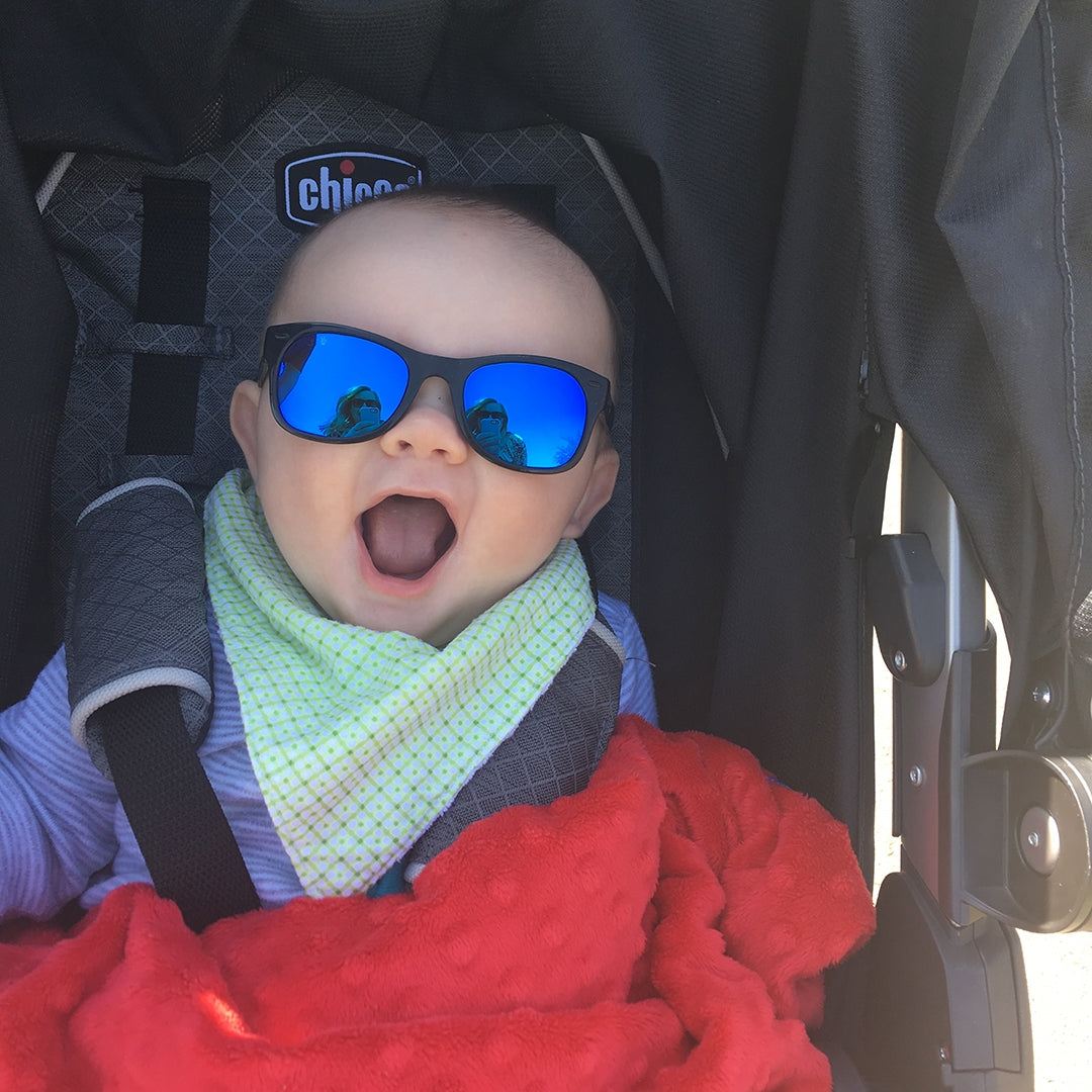 Baby in a stroller wearing sunglasses with a red blanket