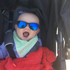 Baby in a stroller wearing sunglasses with a red blanket
