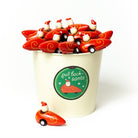 A white ceramic cup with a green circular 'gull beach santa' logo, filled with small red and white Santa-themed toy cars, on a clean white background.