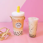 Boba tea with a straw and bubble tea in a clear cup on a pink background
