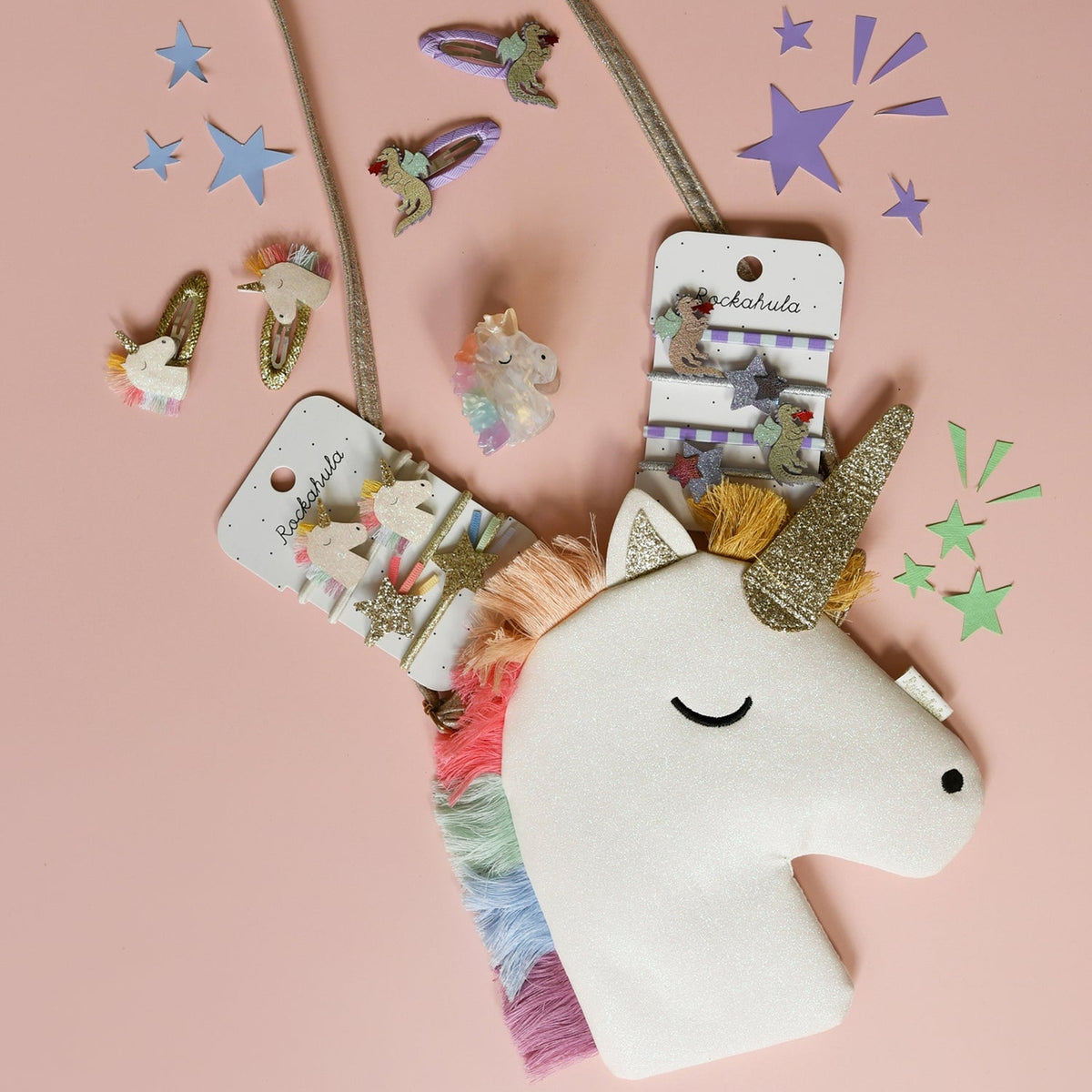 Unicorn-shaped hair accessories with packaging on a pink background