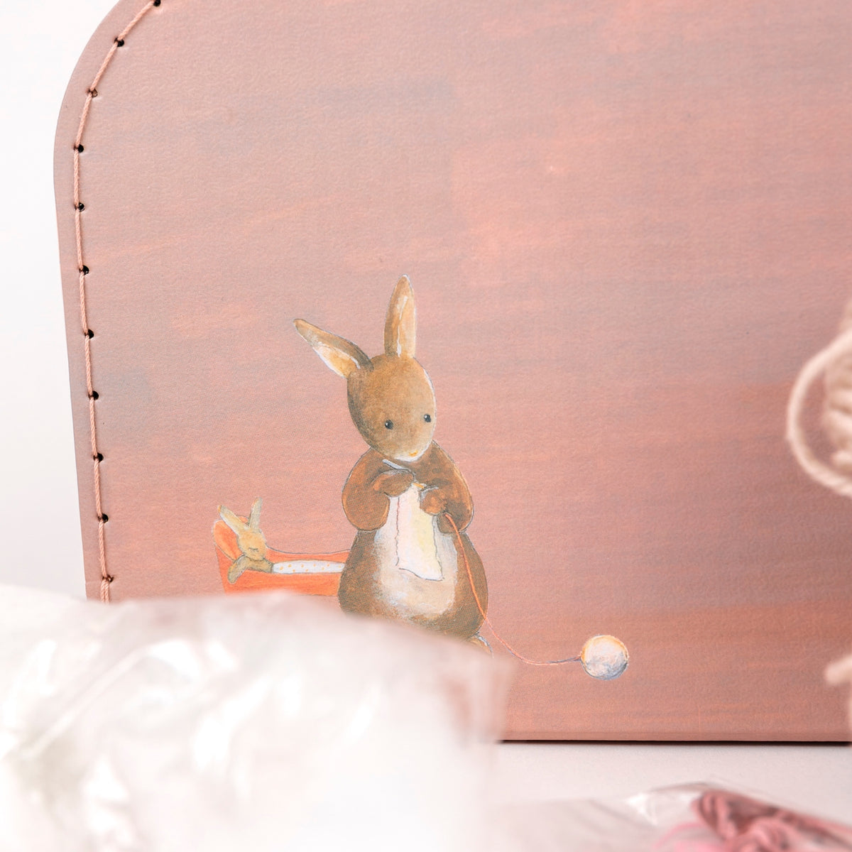 Plush rabbit toy with a book on a soft pink background
