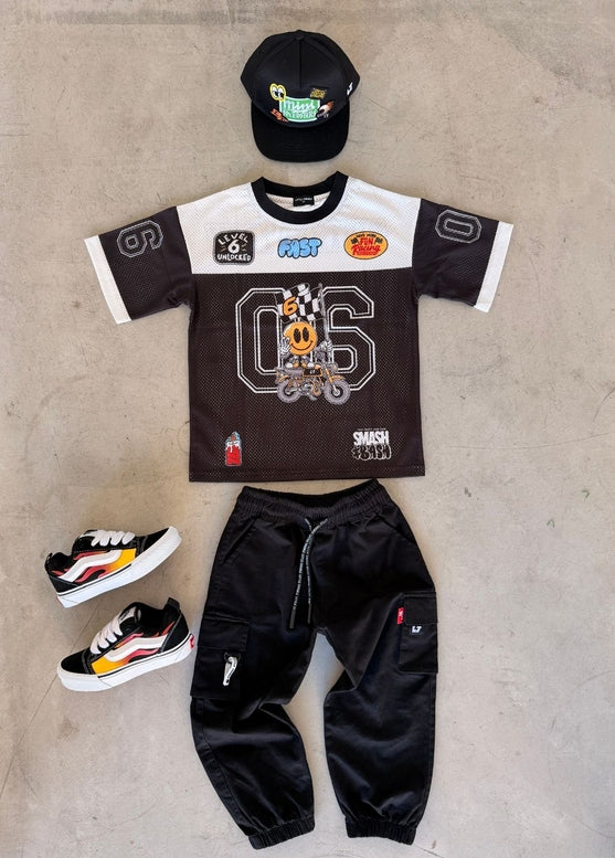 Children's outfit with t-shirt, pants, and shoes on a concrete floor