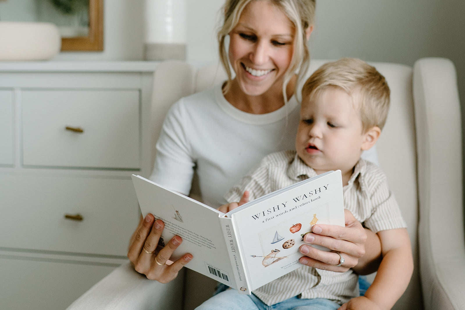 Woman reading a book to a child in a cozy room.