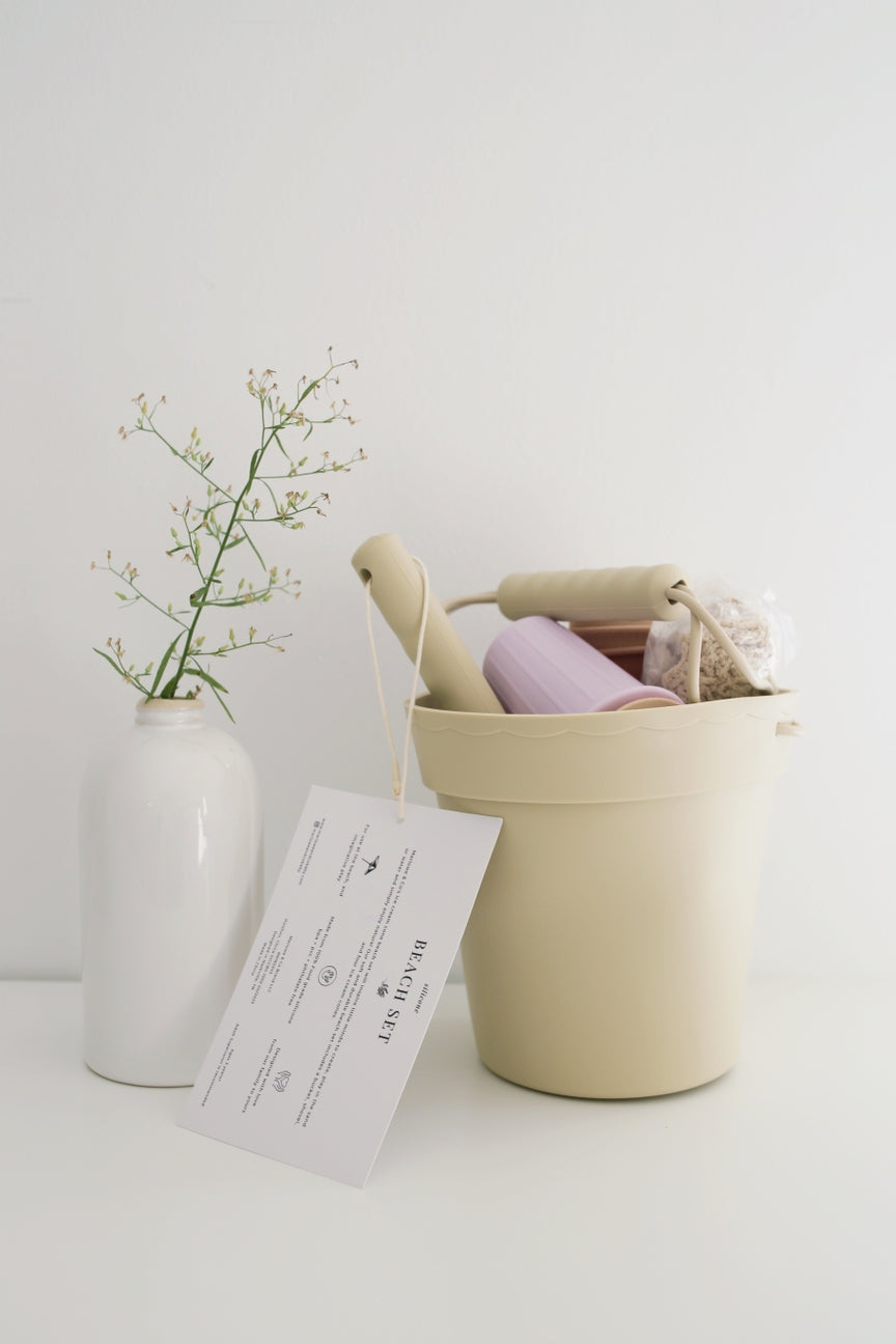 Beige basket with a pink item, white vase with greenery, and 'Marlowe & Co' tag on a light background