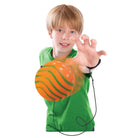 Child holding an orange ball with a black cord, wearing a green shirt on a white background