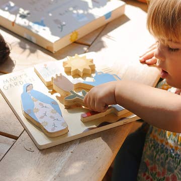 Child playing with a wooden puzzle on a wooden surface