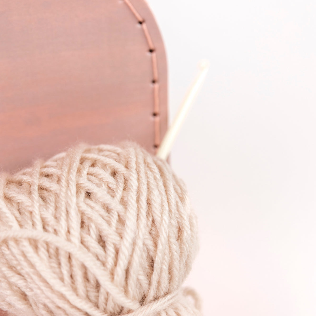 Ball of yarn with knitting needles on a light pink background