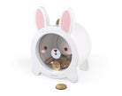 A white rabbit-shaped coin dispenser with pink inner ears and a cute bunny face on the front, shown on a clean white background with coins inside and one in front.