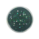 A round clear plastic tub filled with dark green slime containing embedded iridescent glitter, stars, and a rainbow motif, shown against a plain white background.