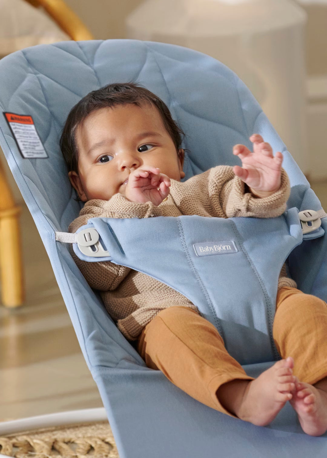 Baby in a blue Bouncer seat with a neutral background