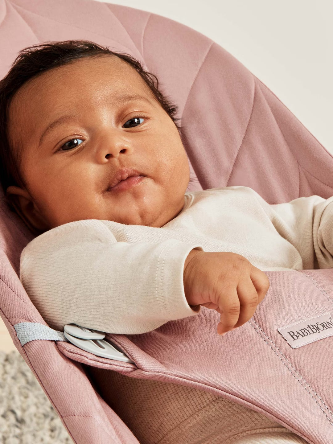 Baby in a pink BabyBjörn carrier looking around