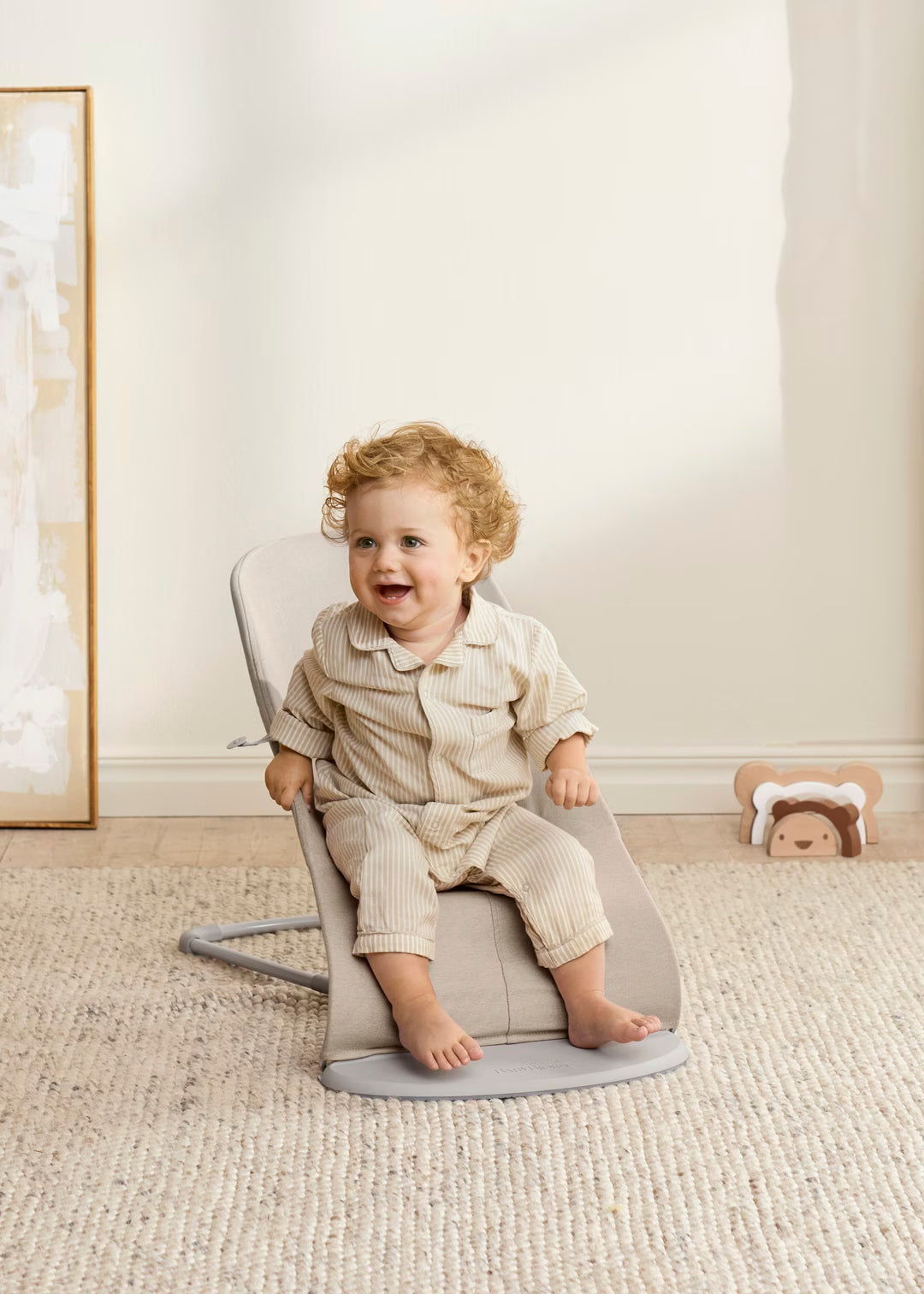 Child sitting on a gray chair in a room with a neutral color scheme