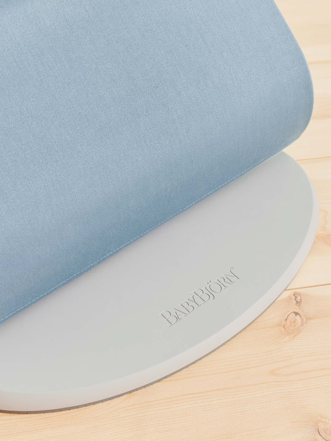 Two baby mats, one blue and one gray, with 'Babybjörn' branding on a wooden surface.