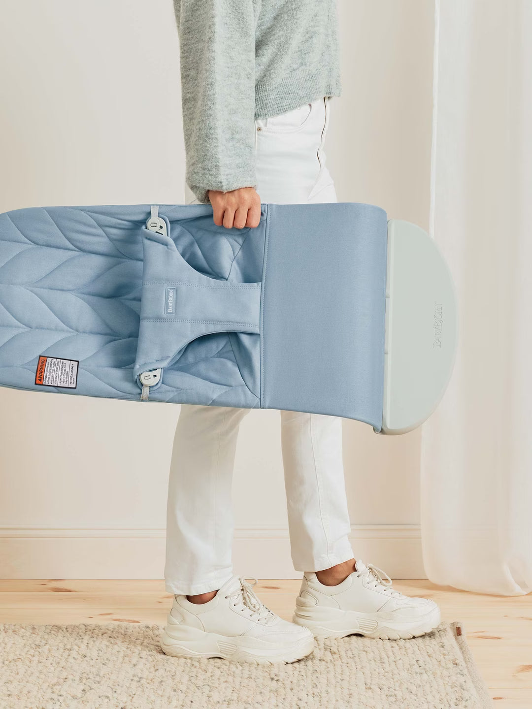 Person holding a light blue quilted bag indoors