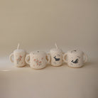 Four ceramic cups with animal illustrations on a beige background