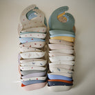 Stack of colorful baby bibs with patterns on a light background