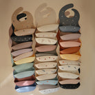 Stack of colorful baby bibs with various patterns on a beige background