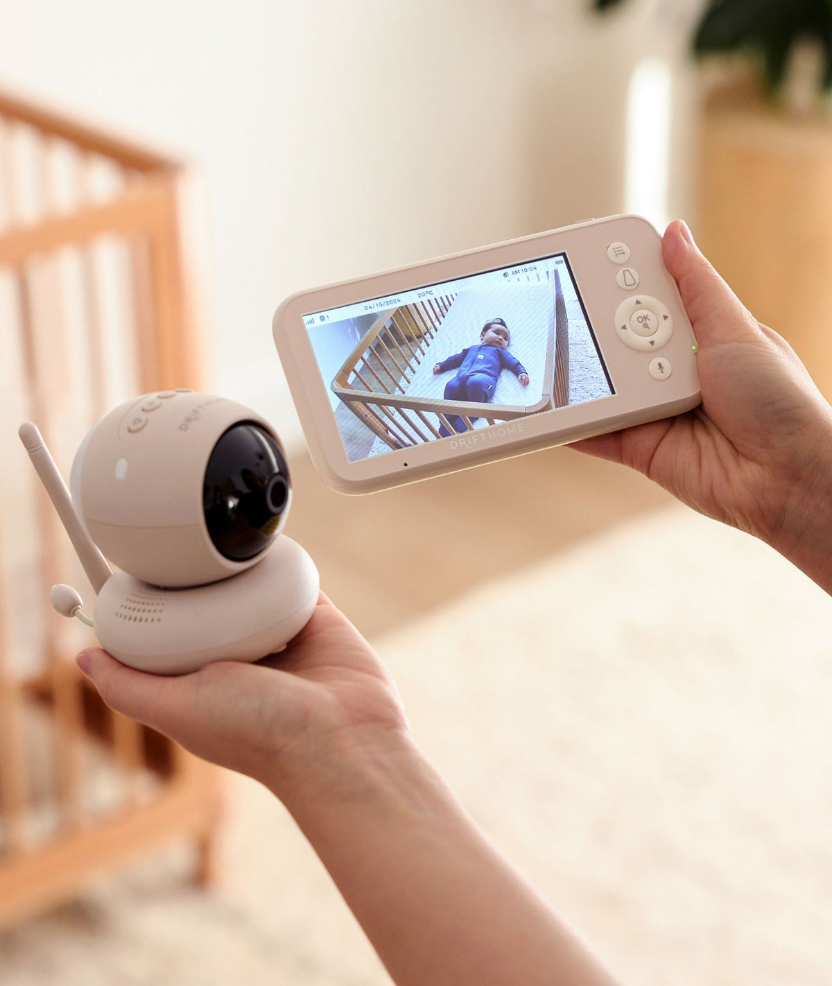 Person holding a baby monitor with a screen displaying a child on a staircase.