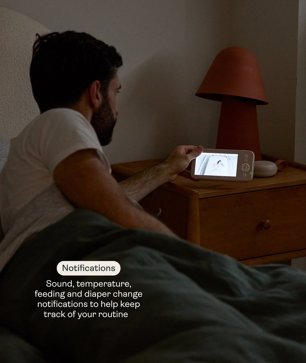 Person sitting in bed using a tablet with a nightstand lamp in the background