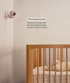 Baby monitor with mounting bracket near a crib in a room.