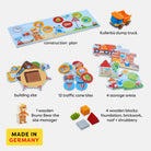 Children's toy set with construction plan, dump truck, traffic cone tiles, and wooden blocks on a white background.