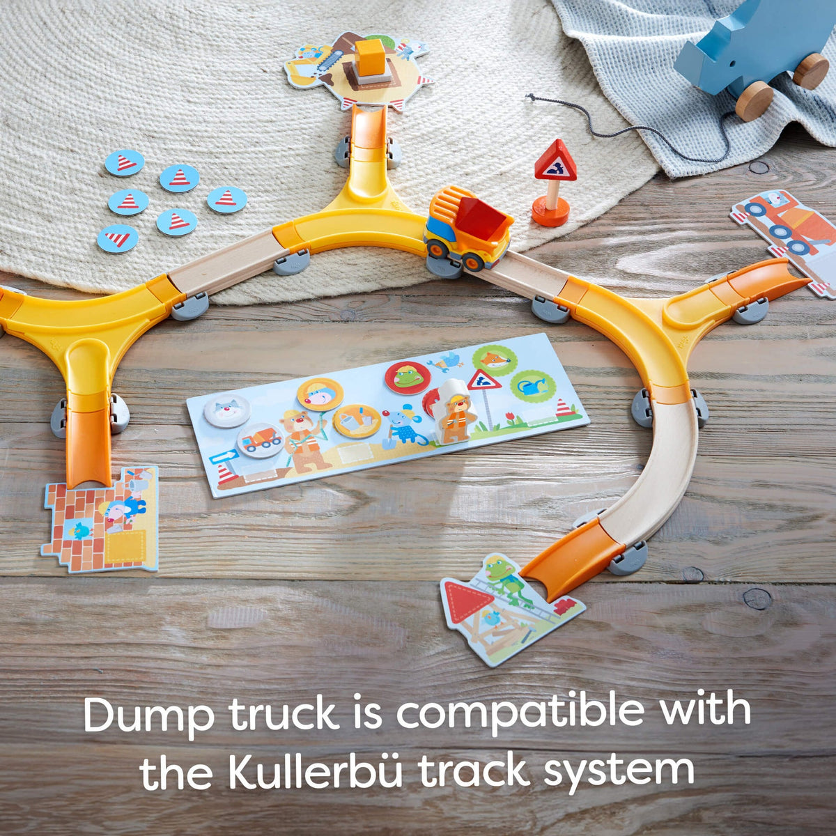 Toy track system with a dump truck on a wooden surface, featuring text about compatibility with Kullerbü track system.
