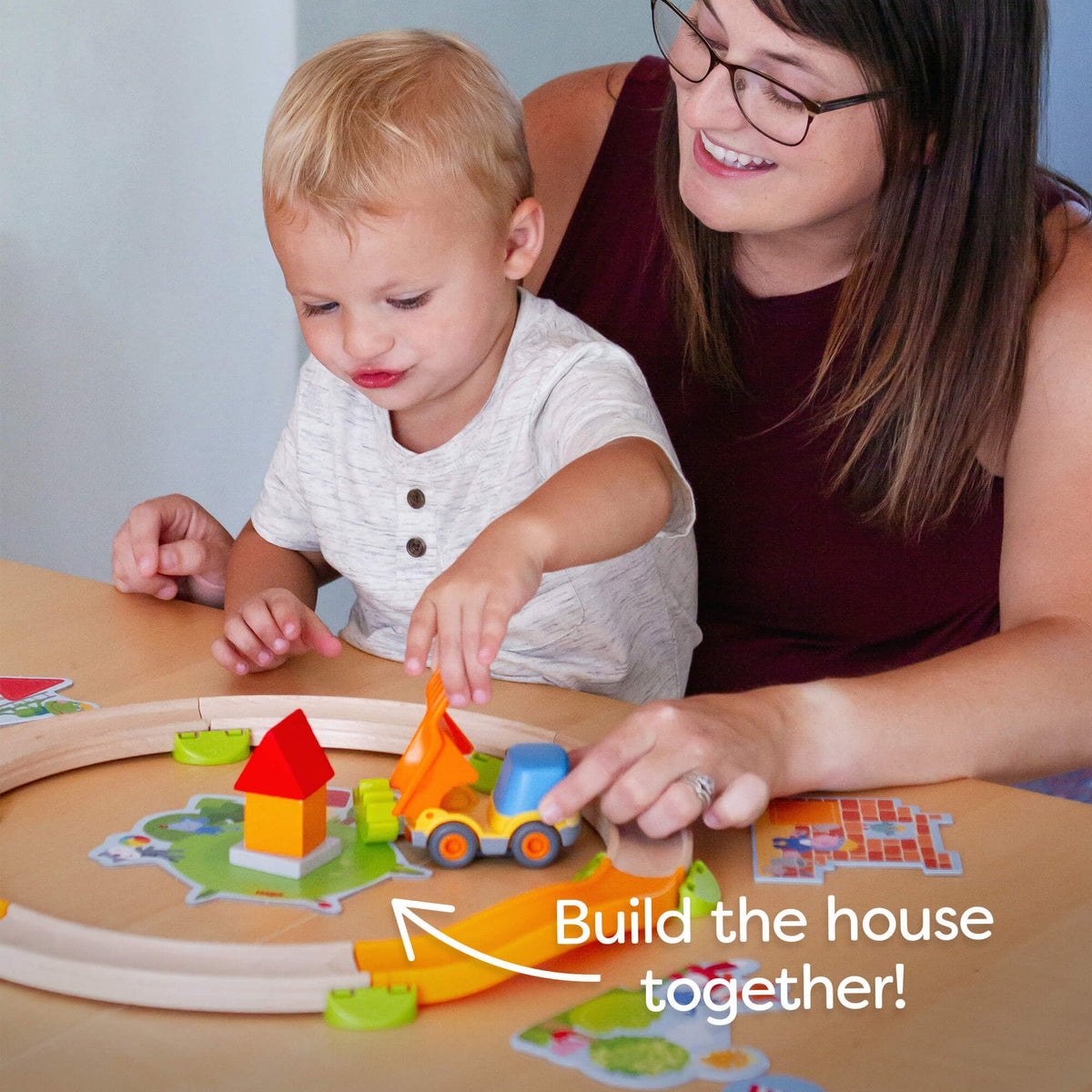 Woman and child playing with colorful building blocks on a table.