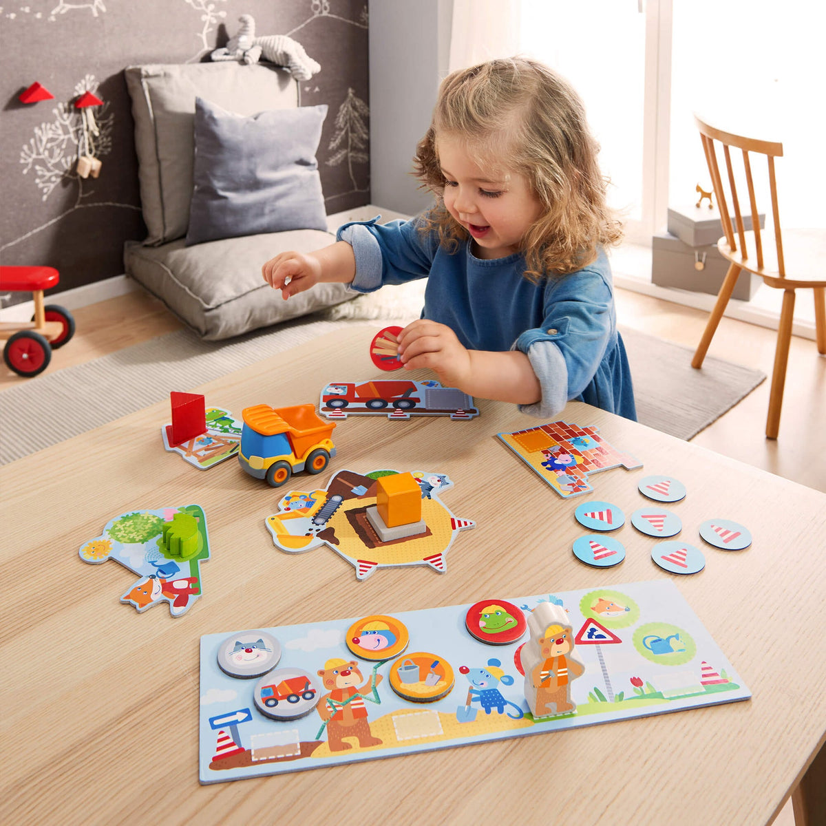 Child playing with educational toys on a wooden floor in a room with a couch and chair.