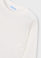Close-up of a cream-colored long-sleeve top by Mayoral, featuring a subtle dotted pattern of small metallic studs and a visible brand label at the collar.