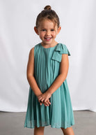 Young girl wearing a teal dress with a bow on a white background