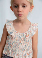 Young girl wearing a floral blouse against a plain background