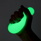 Hand holding a green glowing object against a dark background