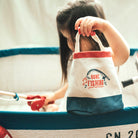 Child holding a 'Gone Fishing' bag in an indoor play area