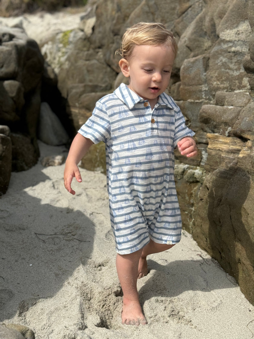 Child in a striped outfit walking on a rocky beach