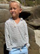 Child wearing a gray hoodie and blue pants standing on rocky terrain